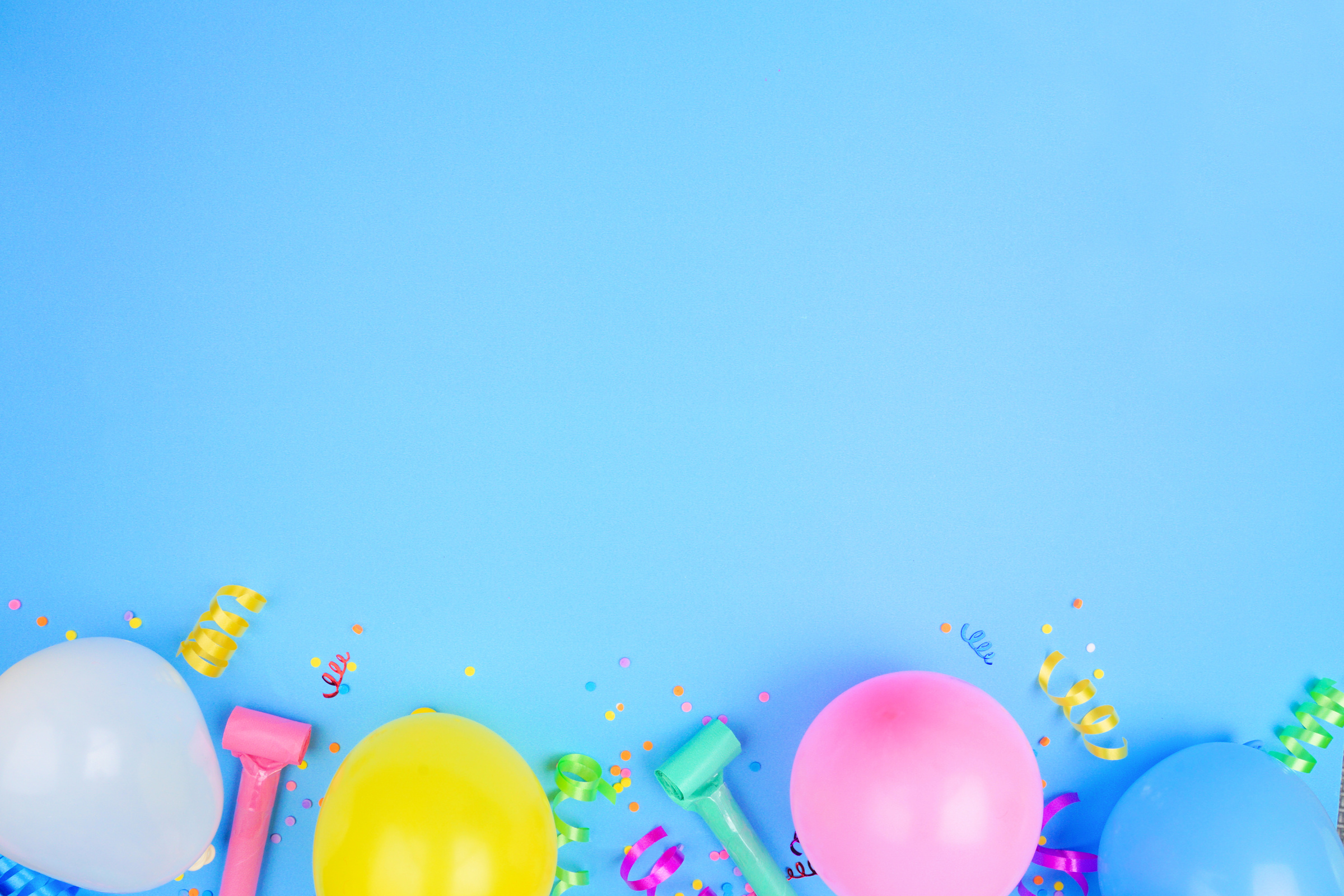 Birthday party bottom border on a blue background with balloons, streamers and confetti